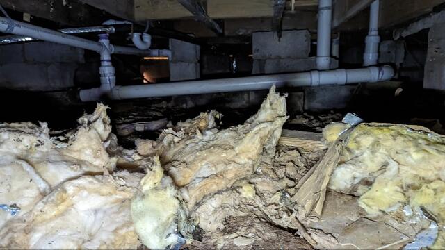 Messy, damp crawl space with a dirt floor and no vapor barrier, allowing moisture to build up beneath the home.