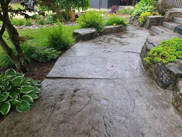 In the front yard, you can see exactly where the settlement began. The heavy, stamped concrete slabs had dropped several inches away from the natural stone garden borders. This created a significant "toe-catcher" hazard for anyone walking to the front door, and left gaps where water could pool and further erode the base.