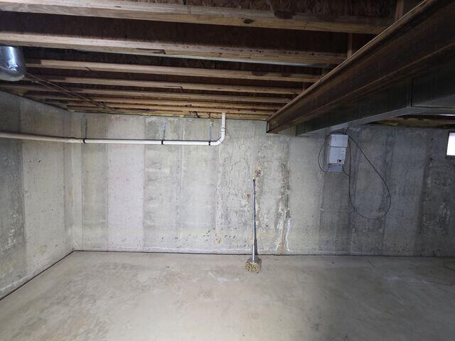 Unfinished basement showing vertical wall cracks, moisture staining, and signs of damp conditions contributing to a musty smell.