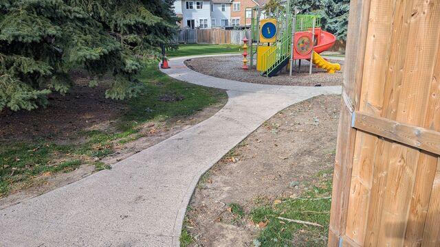 This view shows the high-traffic artery of the complex, where a sinking walkway leads straight to the heart of the community: the playground. You can see how the erosion has pulled the concrete down, creating a jagged path exactly where kids are most likely to be running. The orange cone is a small warning for a big problem that was causing real injuries to the families living here.
