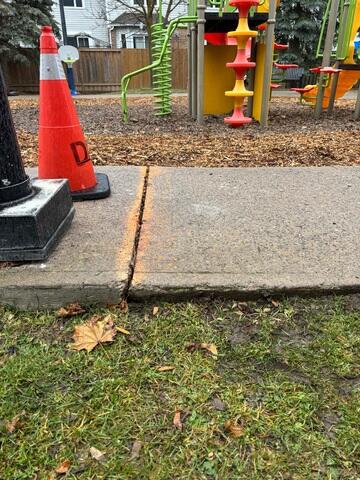 This view highlights the high-traffic route to the playground, where failing subgrade and soil erosion have caused the concrete to settle. The resulting drop-off created a jagged path exactly where kids are most likely to be running. The orange cone marks a major liability that was causing real injuries, requiring a fast solution to stabilize the ground and level the surface.