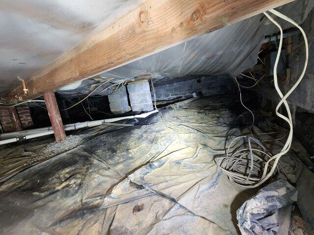 Before encapsulation, the crawl space was cluttered with debris and showed clear signs of dampness and poor insulation.