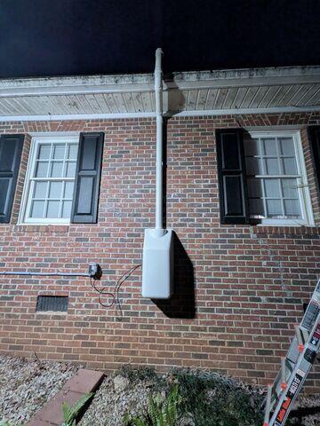 Radon Fan: Exterior-mounted radon fan with protective housing cover, designed for continuous operation and improved system durability.