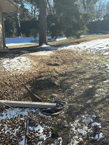 Mid-Install: Holes are dug beyond the foundation wall for anchor placement.
