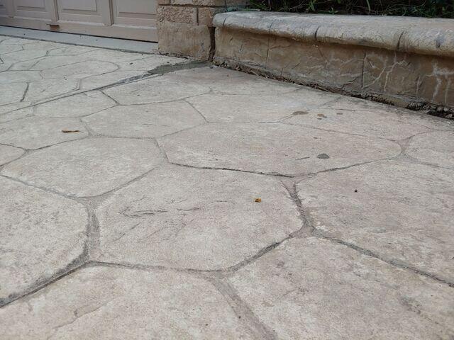 After our poly-injection process, the walkway was lifted and aligned with the brickwork. The gaps were eliminated, and the small injection points are nearly invisible, preserving the stamped concrete's aesthetic.