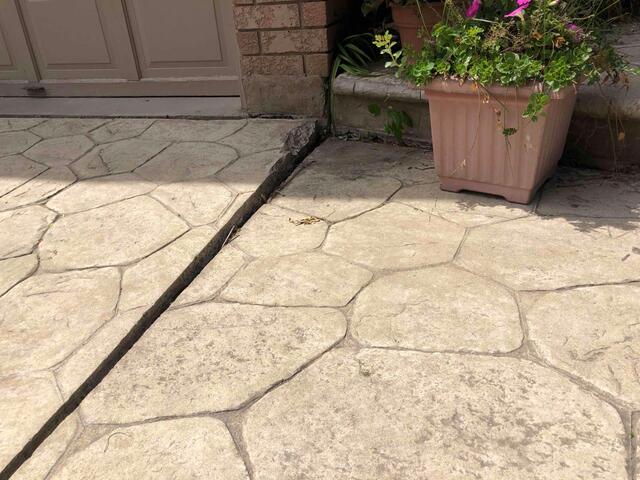 A close-up shows a deep void where the walkway had pulled away from the garage and brick foundation. This gap wasn't just an eyesore; it allowed water to pool, further compromising the soil underneath.