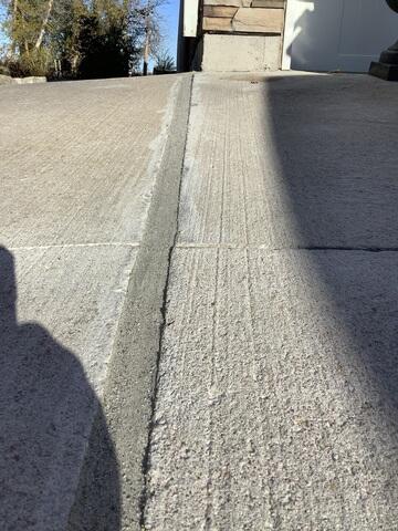 A close-up of the seam between the driveway and garage floor after our poly-injection process. We lifted the sunken slab with high-density polymer and sealed all cracks with premium joint sealant to prevent future water intrusion and stabilize the surface.