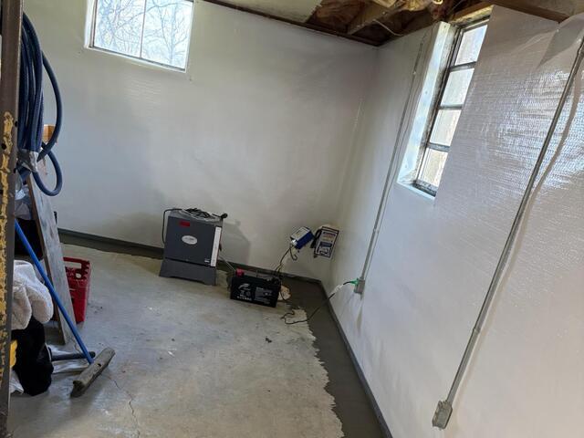 This photo shows our sump pump with a battery backup attached, our SaniDry Sedona dehumidifier, our white vapor barrier, and the freshly concealed drainage system around the perimeter.