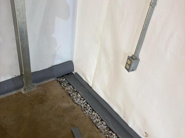 This photo shows where the DryTrak baseboard drain (to the left) meets the WaterGuard subfloor drain (to the right). We all know the saying, "Water flows downhill." The baseboard drains sits higher than the WaterGuard, so water will channel down to the right of this photo.