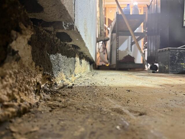 This photo shows a close up of the bottom of the sheared wall. You can see how the wall was sliding inwards over the bottom most visible row of block. The bottom most row of block was not in great condition due to constant moisture exposure. You can also see the role the floor slab plays in holding back the bottom most row of block, which is why the rest of the wall slid over the top of the bottom most row of block. The other half of this row of block is concealed underneath the floor and rests on top of the footing. This is very common for most homes.