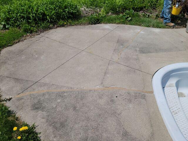 A close-up of the deep, diagonal cracks caused by the lack of subgrade support. Without a solid base to rest on, the weight of the concrete caused it to snap, further demonstrating the impact of the surrounding soil erosion.