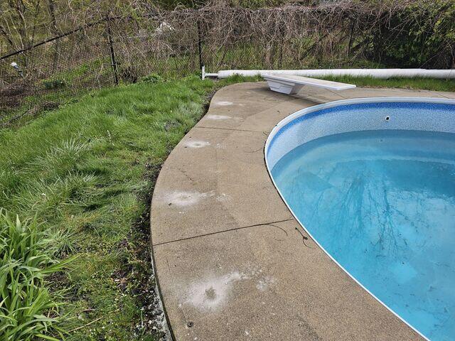 A view from the diving board area showing our injection ports. This perspective illustrates how the lack of a physical retaining border allowed the grass and soil to wash away, leaving the concrete slabs completely unsupported and tilted toward the soft turf.