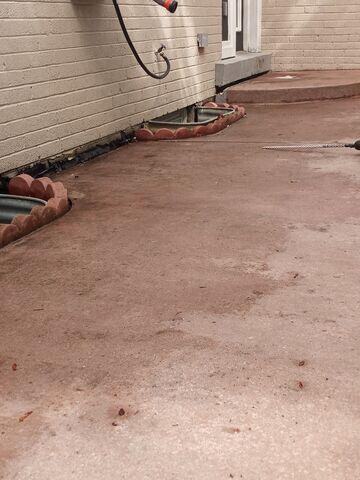The settlement was particularly prominent near the window wells and the home's exterior walls. This view shows how the sinking slabs compromised the perimeter drainage, leaving the foundation vulnerable to water pooling and potential moisture issues if the pitch were not corrected.