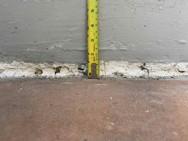 A close-up look at the home's foundation reveals the true scale of the problem: a 1.5-inch drop. This measurement illustrates the substantial void that had formed beneath the concrete, resulting in a dangerous trip hazard and a slope that directed water toward the basement instead of away from it.