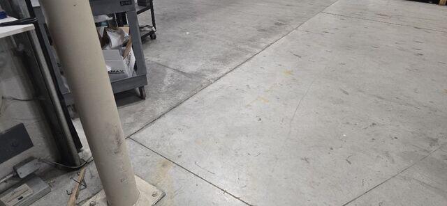 Uneven joints and wear patterns across the warehouse floor, signaling that the slabs have lost subgrade support and are beginning to shift.