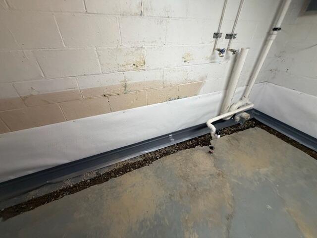 The crew installs the WaterGuard drainage pipe and CleanSpace wall vapor barrier.