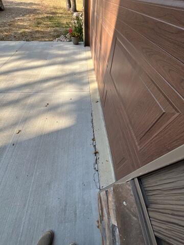 A close-up of where the garage and driveway meet where chipping and cracks can be seen