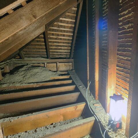 Entering the kneewall, we discovered little to no insulation throughout the space. The kneewall extends around to the right, and as we inspect both sides, we can see there is no insulation barrier to prevent radiant heat from transferring through the adjoining walls during the summer. Looking down into the floor joist bays, we also found no insulation to stop cold air infiltration, which can lead to cold floors, drafts, and uncomfortable rooms during the winter months.