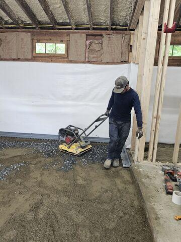 The crew used a mechanical plate compactor to firmly compact the base material before pouring concrete. This created a stable, even foundation for the new garage floor.