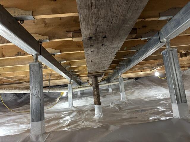 The SmartJack system combines steel support beams, adjustable galvanized steel posts, and engineered support bases to reinforce weakened crawl space floor systems. The steel beams help distribute the structural load across the affected area, while the adjustable posts transfer that weight down to the stable bases below.

CleanSpace is a durable liner installed over the exposed crawl space floor. It separates the home from the earth below and helps reduce moisture vapor entering the crawl space.