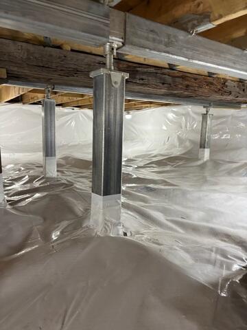 The SmartJack system combines steel support beams, adjustable galvanized steel posts, and engineered bases to stabilize weakened crawl space floor systems. The beams distribute the structural load, while the posts transfer the weight down to stable support locations below.
