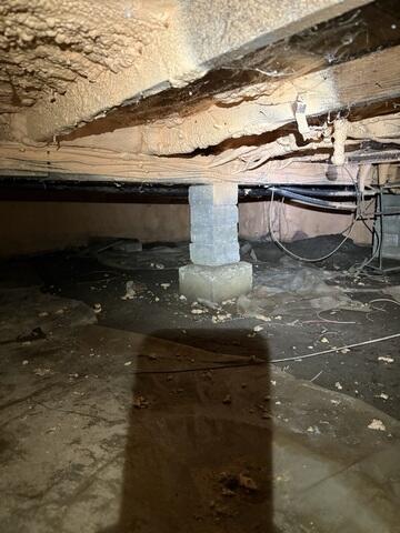 An unfinished crawl space with an aging ground barrier, exposed structural supports, and areas vulnerable to ground moisture. The space needed improved drainage, structural support, and a properly sealed moisture barrier to provide better long-term protection for the home.