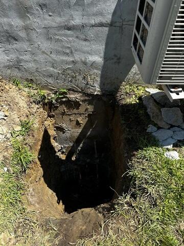 Contractors dig to reach the base or footing of the home's foundation.