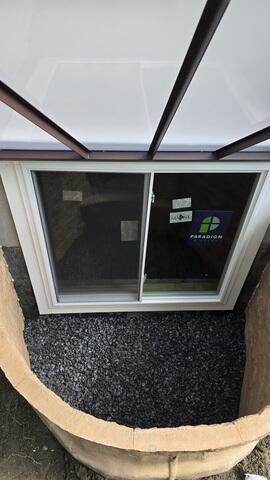 RockWell Egress Window Well - A durable, one-piece window well featuring built-in steps, rigid construction, and a realistic stone-textured appearance.