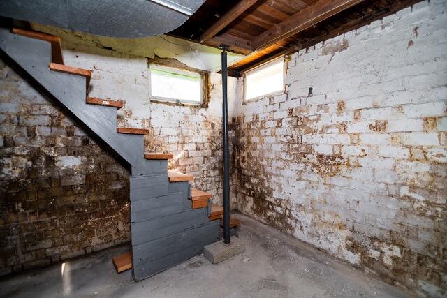 The older brick foundation walls in this basement showed significant signs of deterioration, including gaps in the masonry, loose sections, heavy brown discoloration, and visible water damage.