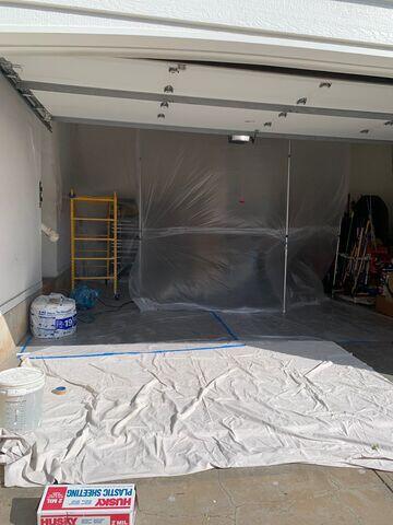 During: Plastic containment and floor protection were set up throughout the garage to help protect stored items and surrounding surfaces during the ceiling repair.