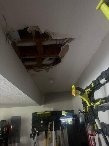 Damaged garage ceiling with drywall removed and the ceiling cavity exposed before the repair process began.