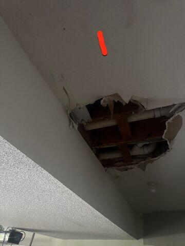 Large opening in an Olathe, KS garage ceiling exposing framing and plumbing before drywall repair.