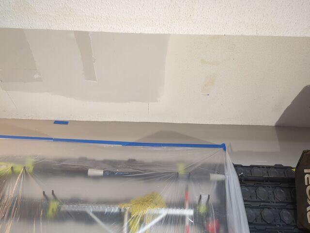 New drywall installed and finished over the garage ceiling opening in preparation for matching the existing popcorn texture.