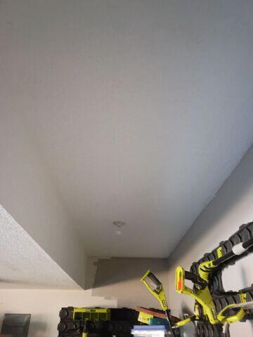 Finished popcorn ceiling after a large drywall patch restored the previously open section of the garage ceiling.