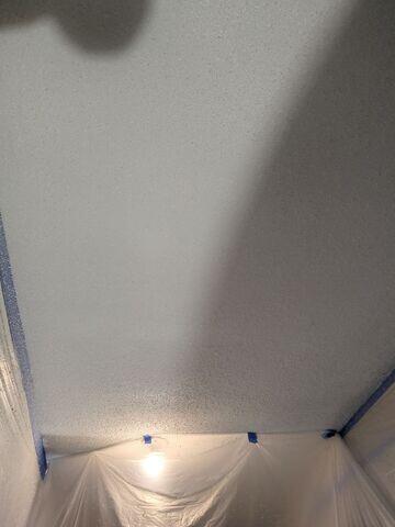 Popcorn texture being applied to the repaired garage ceiling area to blend the new drywall with the surrounding ceiling.