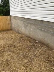 Helical piers were installed, the wall sealed, and the area refilled with dirt and grass seed, preparing the site for the installation of wall anchors.