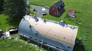 Here you can see the crew installing the new roof on the rounded barn, each IKO Dynasty shingle being carefully hand-sealed in place. Because of the steep, curved slope of this roof, every single shingle had to be secured by hand to make sure it wouldn't slide or lift over time. It's a tedious, extra step that's necessary on a roof with this slope, making all the difference for its long-term durability.