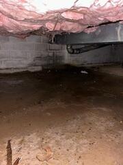 Puddles of standing water on the crawl space floor before repairs.