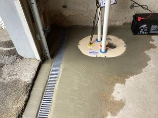 The TripleSafe sump pump takes the water collected by the TrenchDrain XL and sends it out of the garage through the two discharge lines.