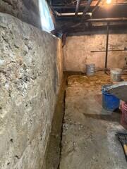 We dug out a channel along the base of the basement wall to install the drainage system securely. The basement had a history of water seepage during heavy rains.