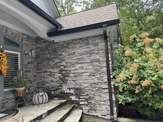 After: We updated his current gutters and downspouts for a more polished sleek look with the black color AND corrected the issue with downpour next to front door by installing Raindrop gutter protection on top of the open K-style gutters.