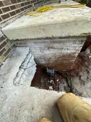 Helical pier bracket installed under the porch to provide deep foundational support.