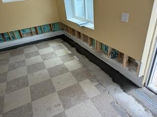 This photo shows a fresh concrete layer we floated over our WaterGuard drains to neatly conceal them. You can see the old concrete layer from the other company, which extends about six inches farther away from the perimeter than our system does.