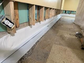 This photo shows our exposed WaterGuard system. Underneath the white tape that lies parallel with the floor is where the top of our WaterGuard drains sit. The homeowner didn't trust the previous company to come back and waterproof the rest of the basement, since their system had already failed and the warranty wasn't honored. They wanted us to install a full, reliable system so they could completely finish their basement floor without worrying about water entering anywhere.