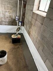 This was what the system looked like upon completion. We covered the drains with a fresh concrete layer. Although concealed, the WaterGuard has a tiny wall flange sticking up out of the floor and against the walls to be able to capture wall leaks. The TripleSafe sump pump was fitted with three different pumps inside the liner, including one pump that is backed by a battery backup system in case of power failure.
