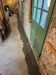 Concrete restored over the trench drain and WaterGuard from the same angle, blending seamlessly with the existing basement floor.