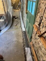 Trench drain tied into the WaterGuard system after backfilling with clean gravel and sealing with moisture-proof tape to block moisture transfer.