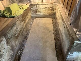 This photo shows an open trench with weep holes drilled into the coves. This trench was dug on top of the footing of the home. Our WaterGuard is always installed on the top of the footing to ensure it stays out of the "mud-zone" found below and next-to the footing. Before jackhammering the floor, we made sure to protect the space from dust with plastic. This included covering the vents and all the homeowners items.