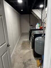 A functional laundry area with a finished wall system and recessed lighting. The exposed concrete floor keeps it practical, while the clean walls and trim tie the space into the rest of the finished basement.