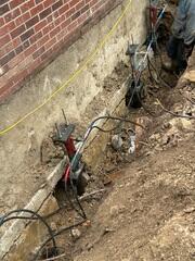 This photo provides a closer look at the pier brackets secured beneath the footing. At this stage of the project, our hydraulic attachments were connected, allowing us to carefully lift and relevel the structure.